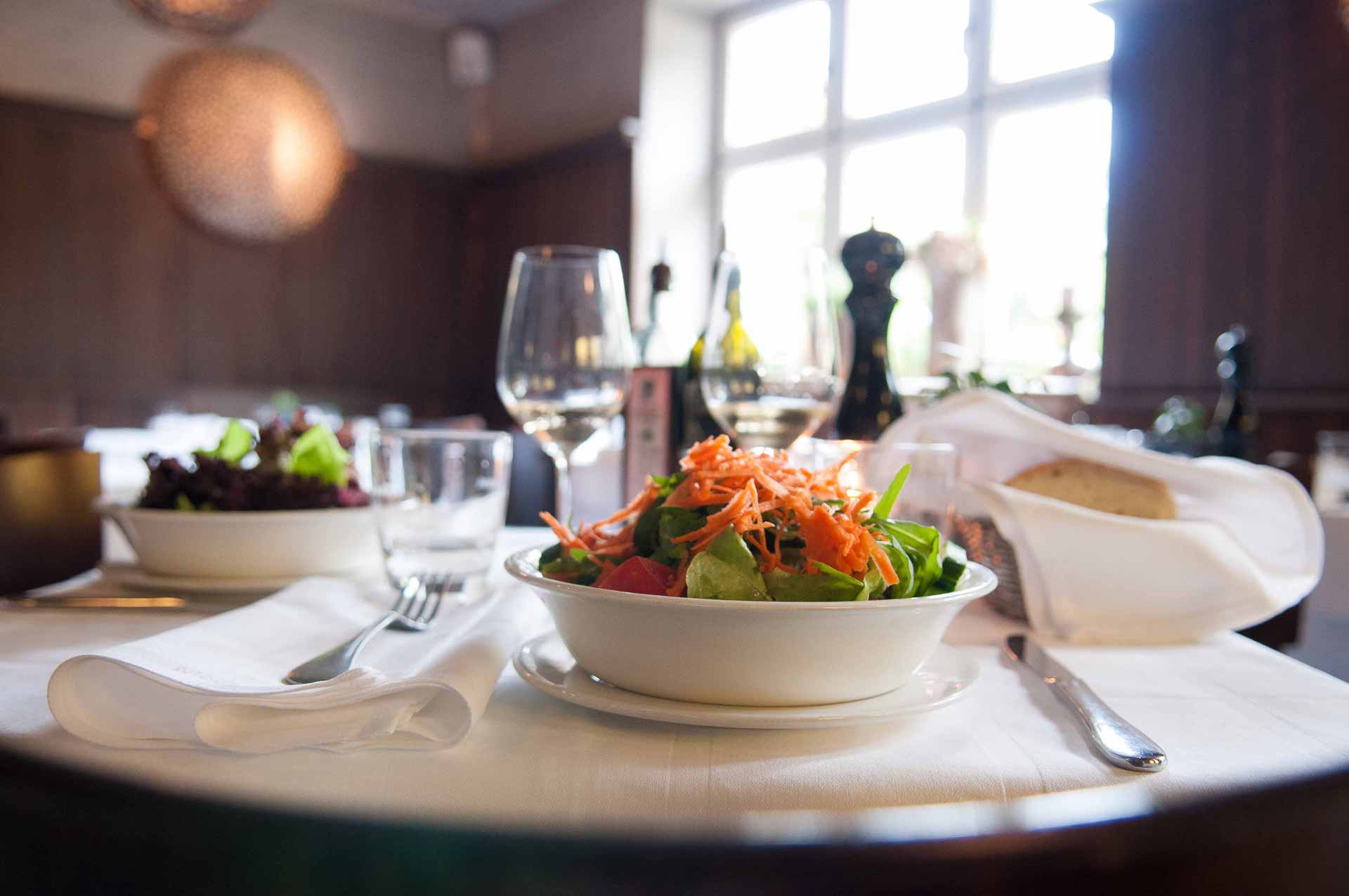 Gedeckter Tisch mit Salat und Weinglas
